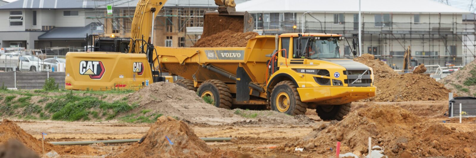 Yellow excavator loading soil into an articulated dump truck in Clyde North, Victoria