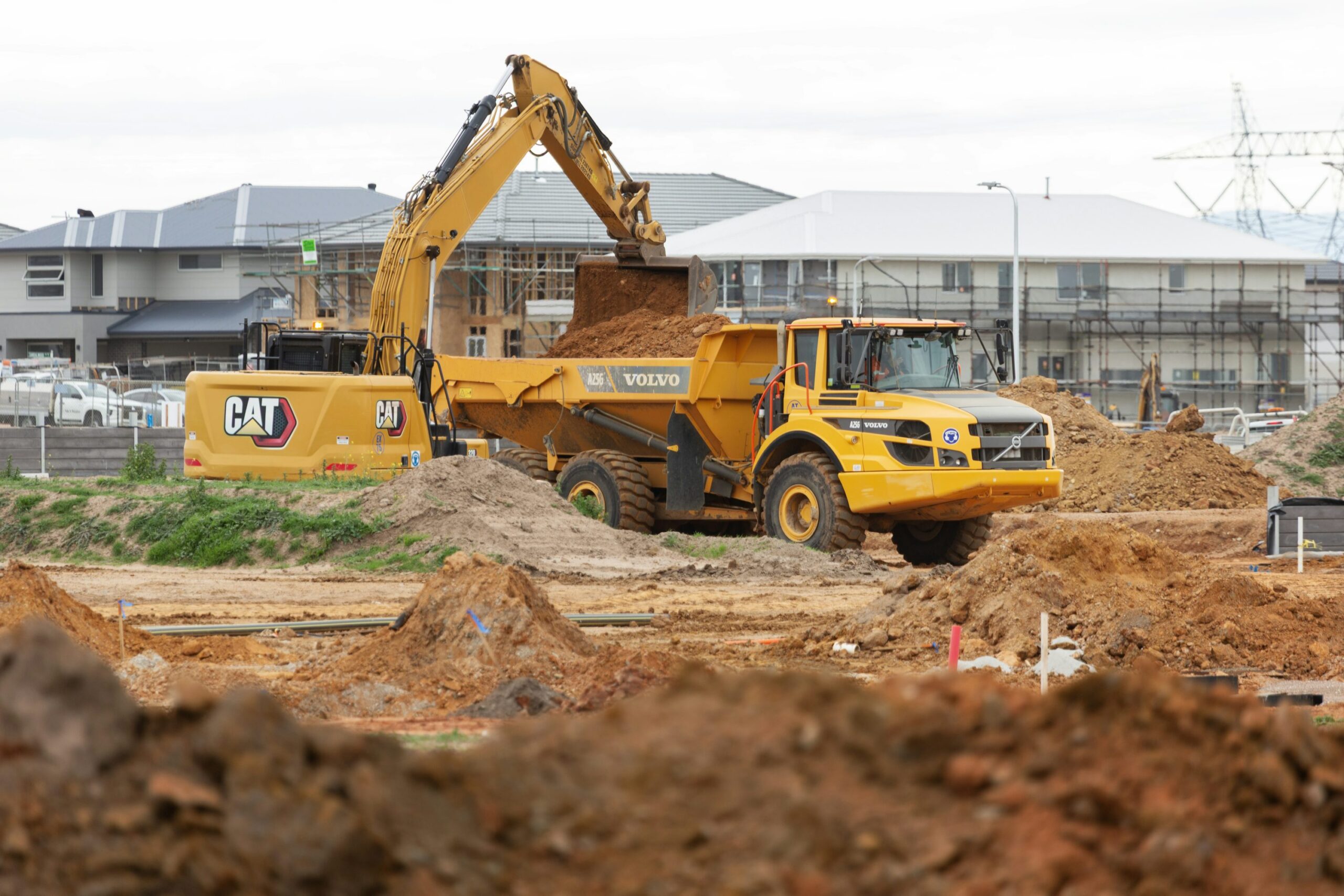 Yellow excavator loading soil into an articulated dump truck in Clyde North, Victoria