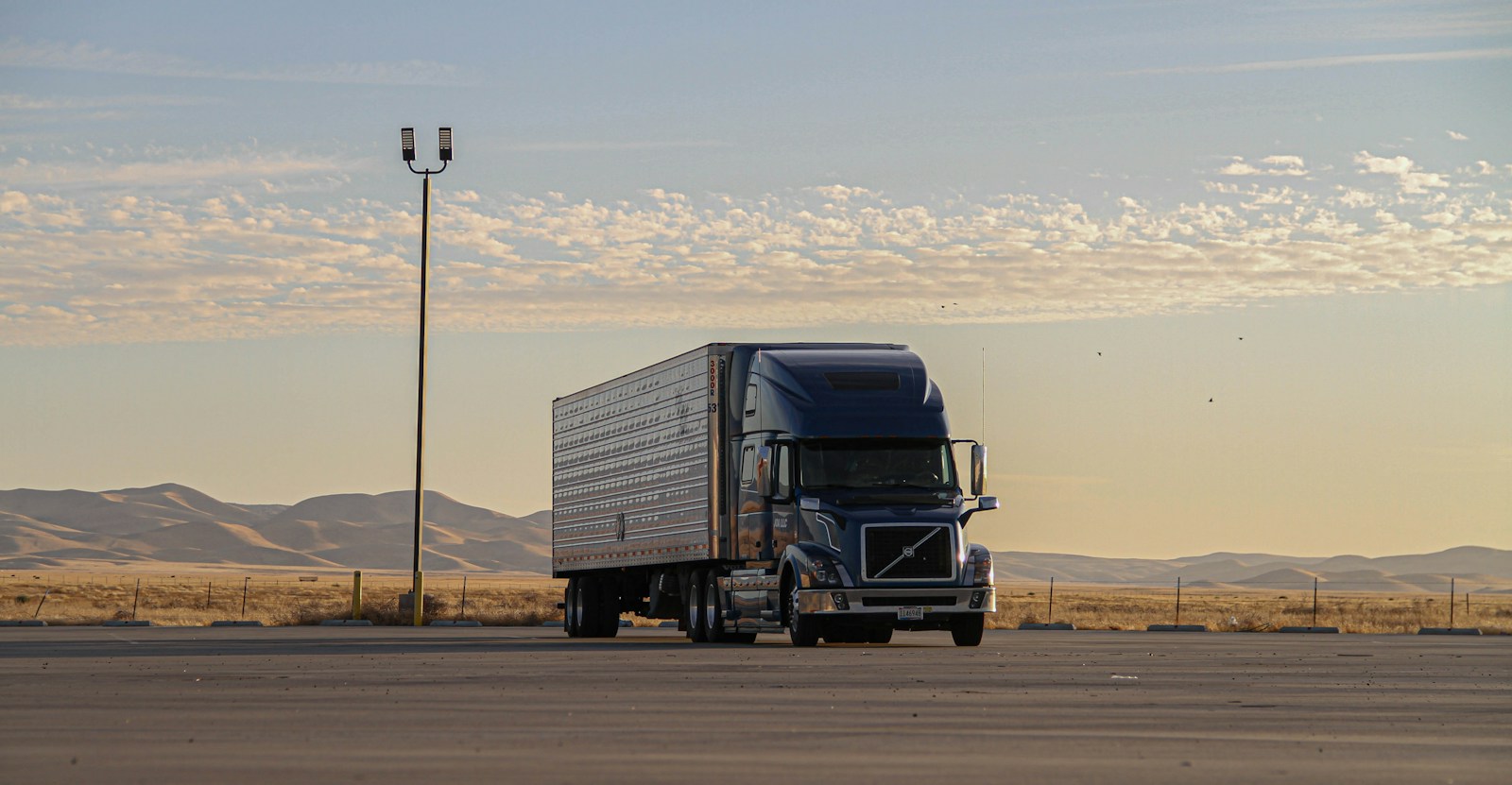Articulated freight truck parked beside open countryside
